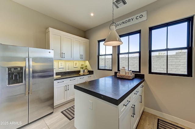 kitchen featuring white cabinetry, stainless steel fridge with ice dispenser, light tile patterned floors, and hanging light fixtures