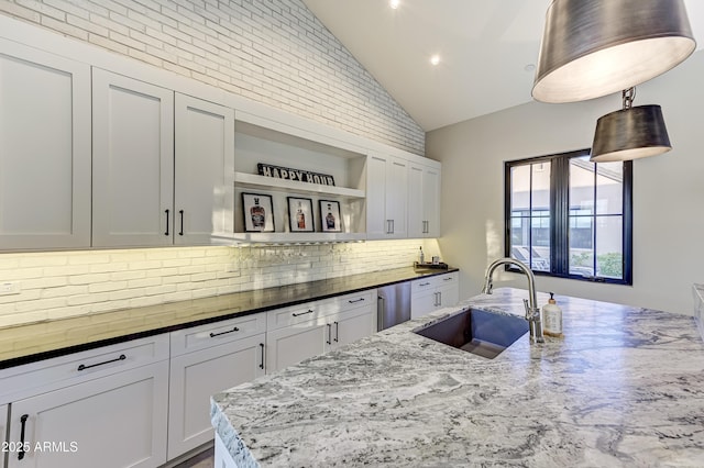 kitchen featuring decorative backsplash, light stone counters, stainless steel dishwasher, sink, and white cabinets