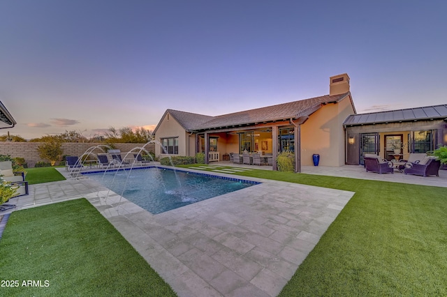 pool at dusk with pool water feature, a patio area, and outdoor lounge area