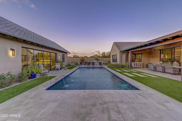 pool at dusk with pool water feature and a patio