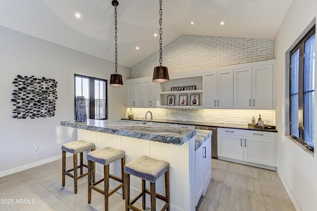 kitchen featuring white cabinetry, pendant lighting, lofted ceiling, a breakfast bar area, and light tile patterned floors