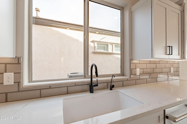 kitchen featuring a healthy amount of sunlight, light stone countertops, and white cabinetry