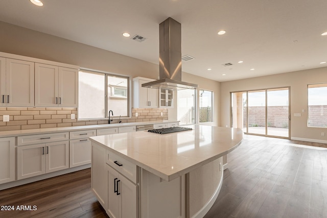 kitchen with backsplash, island range hood, white cabinets, dark hardwood / wood-style floors, and a kitchen island