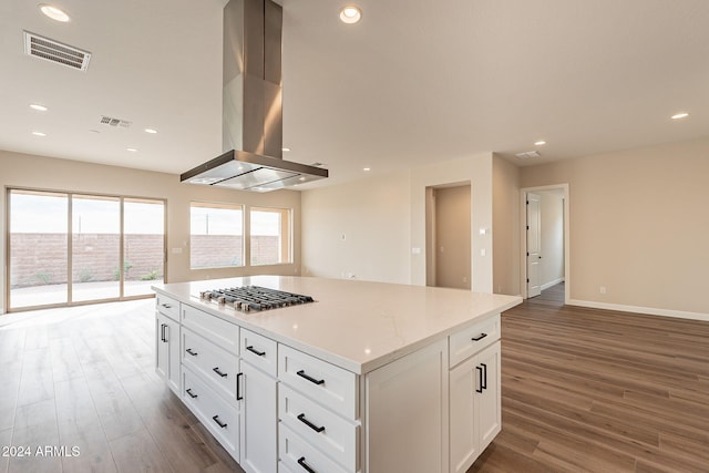 kitchen with white cabinets, wall chimney exhaust hood, dark hardwood / wood-style floors, and stainless steel gas stovetop