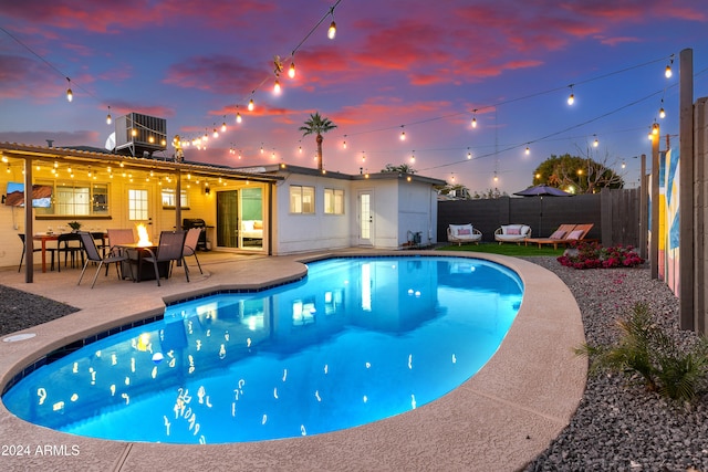 pool at dusk featuring a patio area, cooling unit, and a fire pit