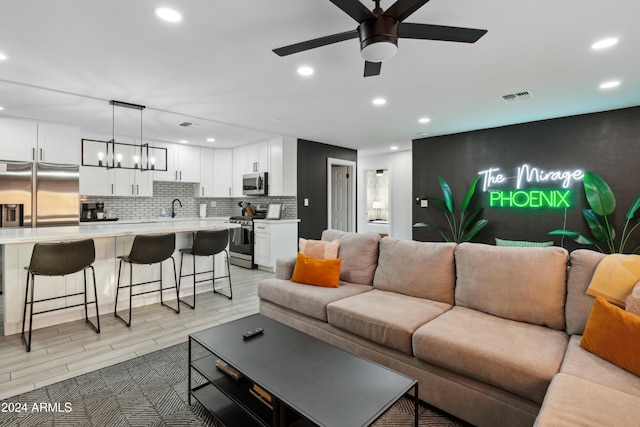 living room featuring ceiling fan, light hardwood / wood-style floors, and sink