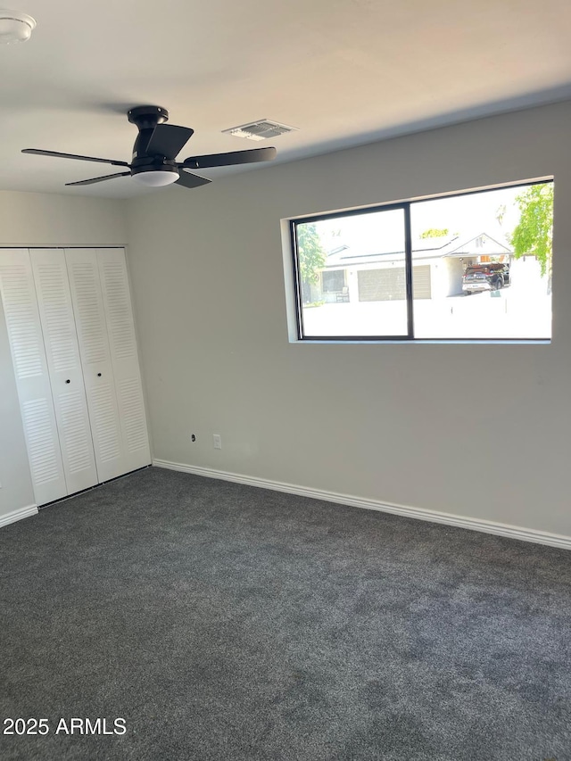 unfurnished bedroom with ceiling fan and dark colored carpet