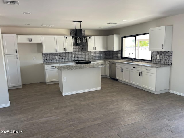 kitchen featuring stainless steel dishwasher, white cabinets, sink, and a kitchen island