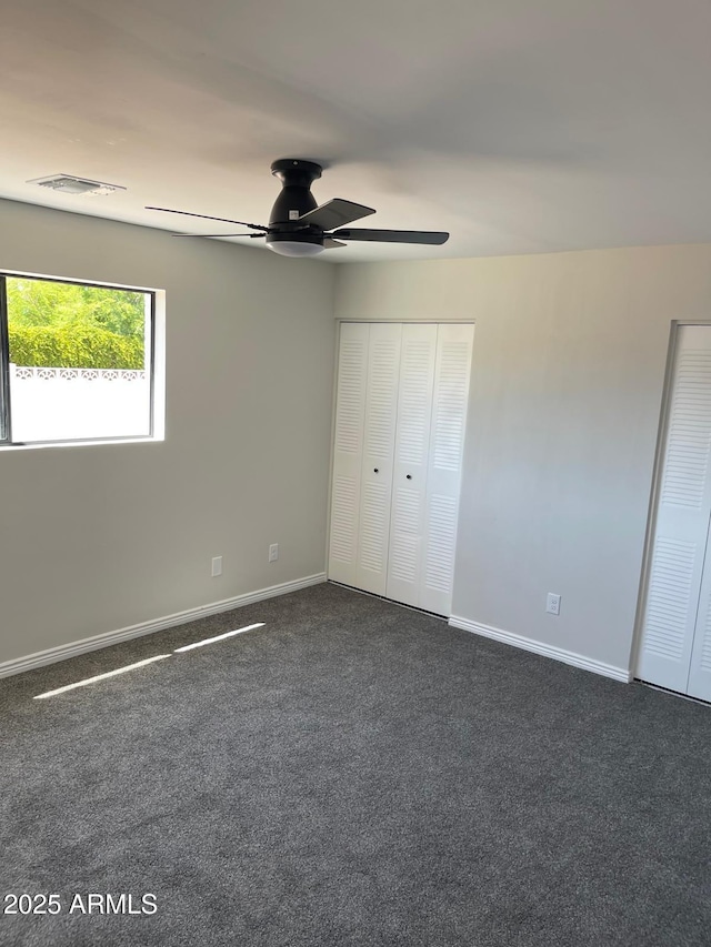 unfurnished bedroom featuring ceiling fan and dark colored carpet