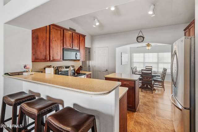 kitchen featuring kitchen peninsula, stainless steel appliances, lofted ceiling, and ceiling fan