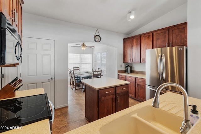 kitchen with sink, vaulted ceiling, stove, stainless steel refrigerator, and ceiling fan