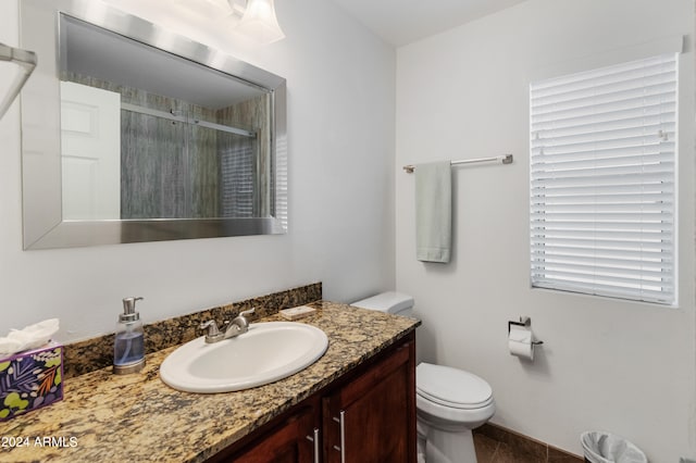 bathroom with vanity, toilet, and a shower with door