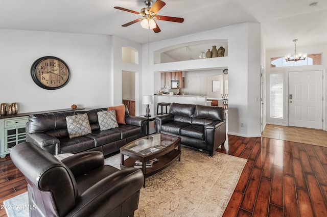 living room with ceiling fan with notable chandelier, high vaulted ceiling, and dark hardwood / wood-style floors