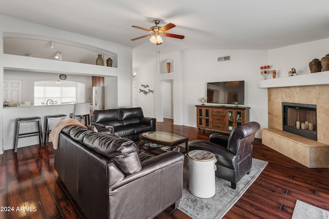 living room featuring lofted ceiling, dark wood-type flooring, a fireplace, and ceiling fan