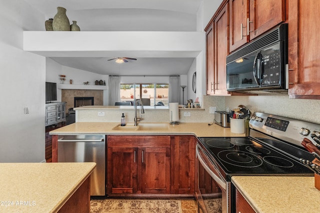 kitchen featuring a tile fireplace, sink, vaulted ceiling, appliances with stainless steel finishes, and ceiling fan