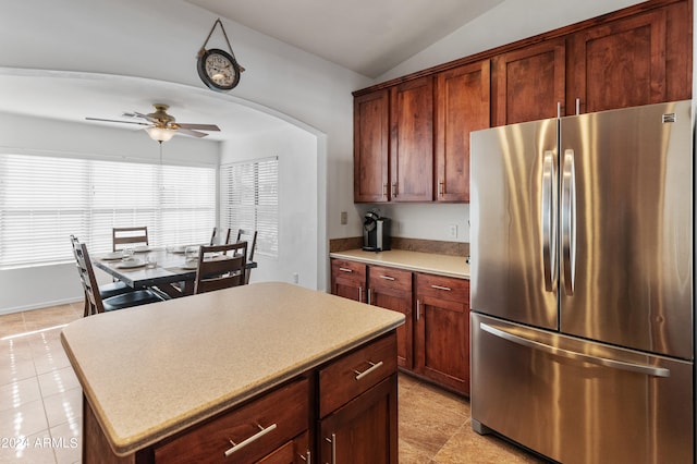 kitchen featuring a kitchen island, vaulted ceiling, light tile patterned floors, stainless steel refrigerator, and ceiling fan