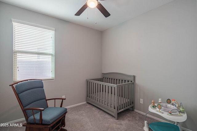 carpeted bedroom featuring ceiling fan and a crib