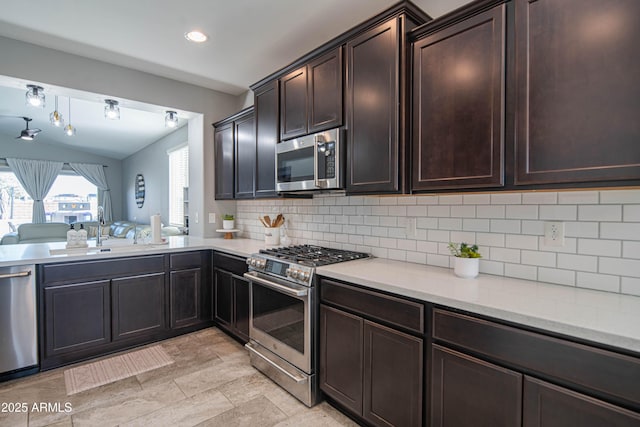 kitchen with stainless steel appliances, sink, dark brown cabinetry, and decorative backsplash