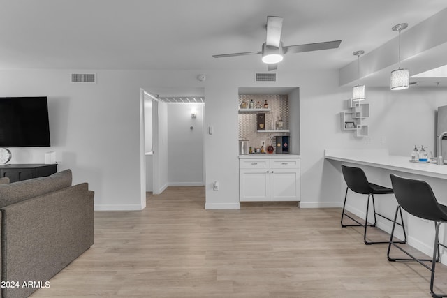 living room with light wood-type flooring, bar area, and ceiling fan