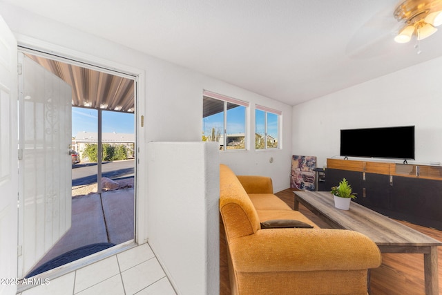 living room with lofted ceiling, a healthy amount of sunlight, ceiling fan, and light tile patterned floors