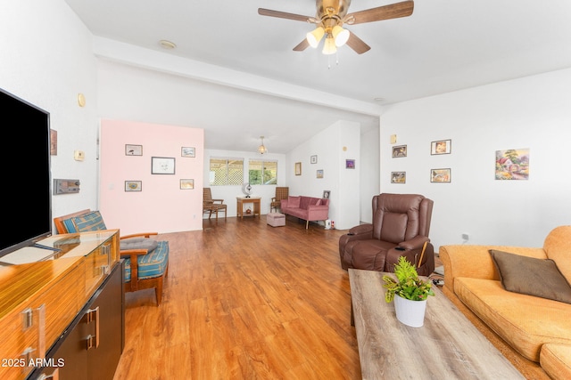 living room with ceiling fan, lofted ceiling with beams, and light wood-type flooring