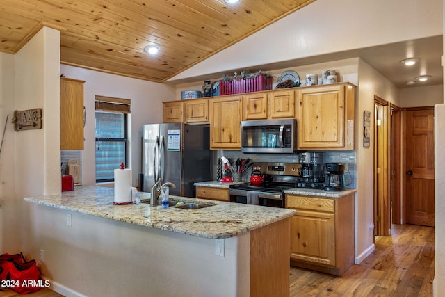 kitchen with vaulted ceiling, light wood-type flooring, appliances with stainless steel finishes, sink, and kitchen peninsula