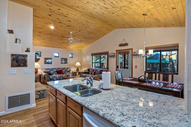 kitchen featuring light hardwood / wood-style flooring, decorative light fixtures, ceiling fan with notable chandelier, light stone counters, and sink