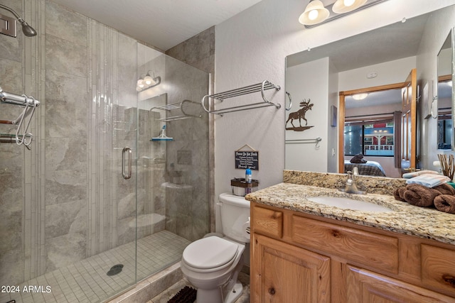 bathroom featuring a shower with door, vanity, and toilet