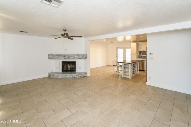 unfurnished living room featuring ceiling fan, a textured ceiling, and french doors