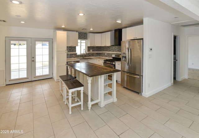 kitchen with wood counters, a center island, white cabinets, and appliances with stainless steel finishes