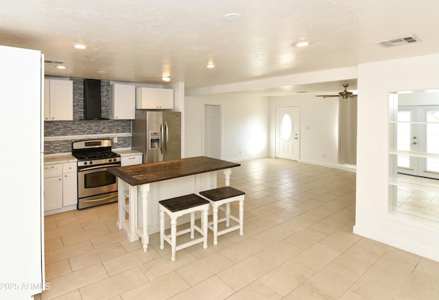 kitchen featuring stainless steel appliances, a breakfast bar, butcher block countertops, and white cabinets