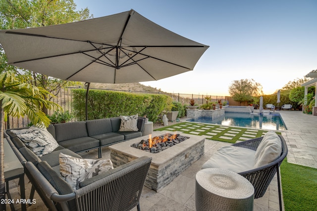 patio terrace at dusk with a fenced in pool, pool water feature, and an outdoor living space with a fire pit