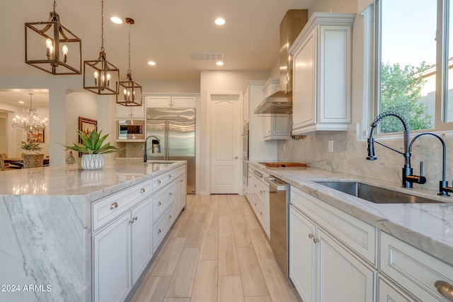 kitchen featuring pendant lighting, tasteful backsplash, an island with sink, white cabinetry, and light stone counters