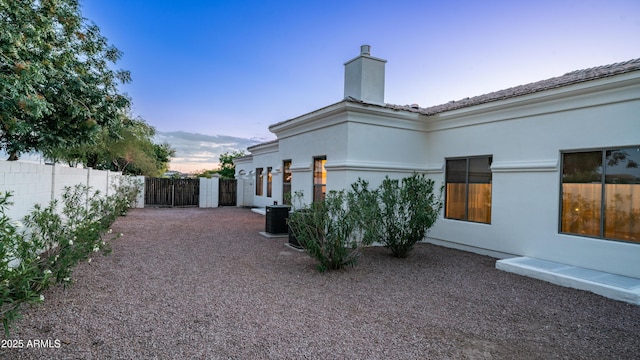 3126 E Fruitvale Ct, Gilbert, AZ 85297 - back of house at dusk with a chimney, central air condition unit, and stucco siding