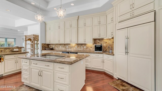3126 E Fruitvale Ct, Gilbert, AZ 85297 - kitchen featuring paneled built in refrigerator, a tray ceiling, a chandelier, black electric cooktop, and dark wood-style flooring