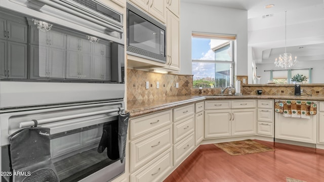 3126 E Fruitvale Ct, Gilbert, AZ 85297 - kitchen with black microwave, double oven, wood finished floors, a chandelier, and decorative backsplash