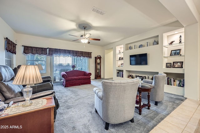 living room featuring ceiling fan, tile patterned flooring, built in features, and a fireplace