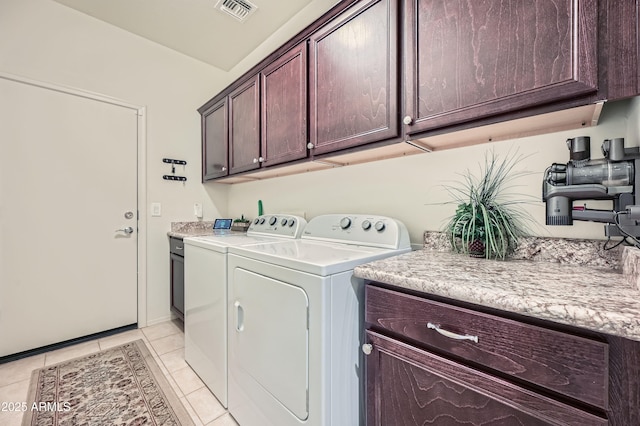 clothes washing area with cabinets, light tile patterned floors, and washer and clothes dryer