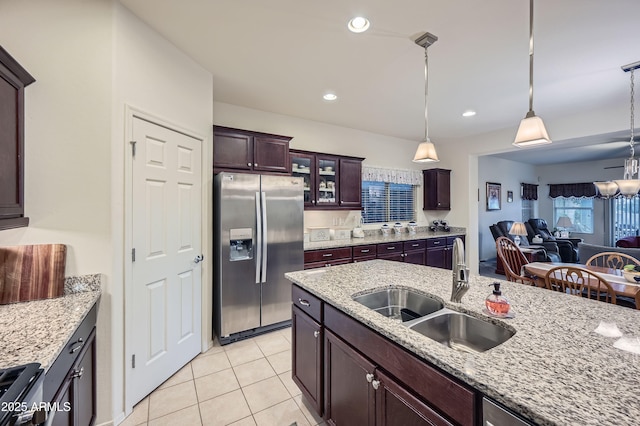 kitchen with appliances with stainless steel finishes, light tile patterned flooring, light stone countertops, pendant lighting, and sink