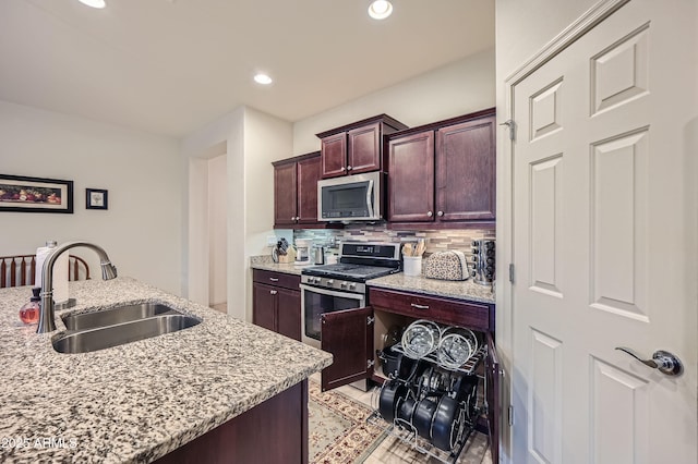 kitchen with stainless steel appliances, decorative backsplash, light stone counters, and sink