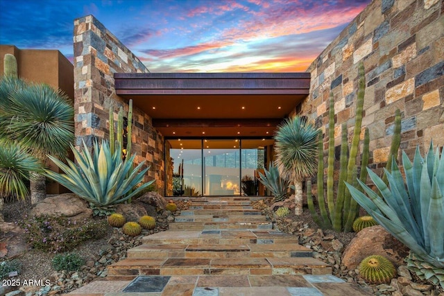 exterior entry at dusk with stone siding