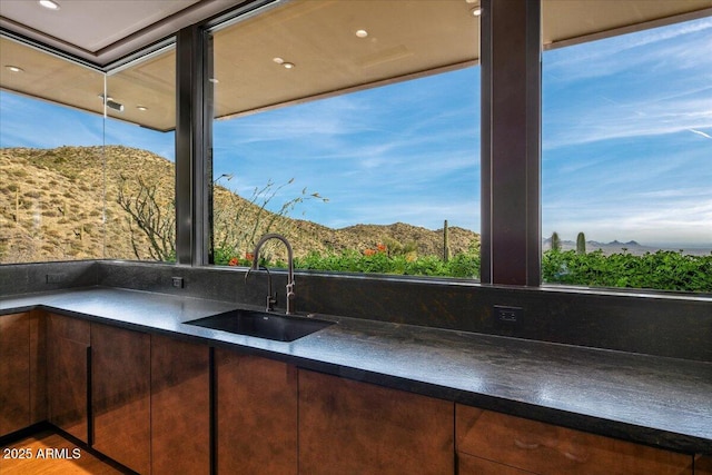 kitchen featuring a sink, a mountain view, dark countertops, and dark brown cabinets