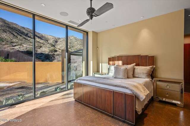 bedroom with access to outside, a mountain view, a ceiling fan, and a wall of windows