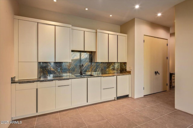 kitchen featuring dark stone countertops, decorative backsplash, a sink, and recessed lighting