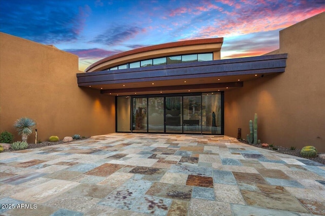 view of exterior entry featuring a patio and stucco siding
