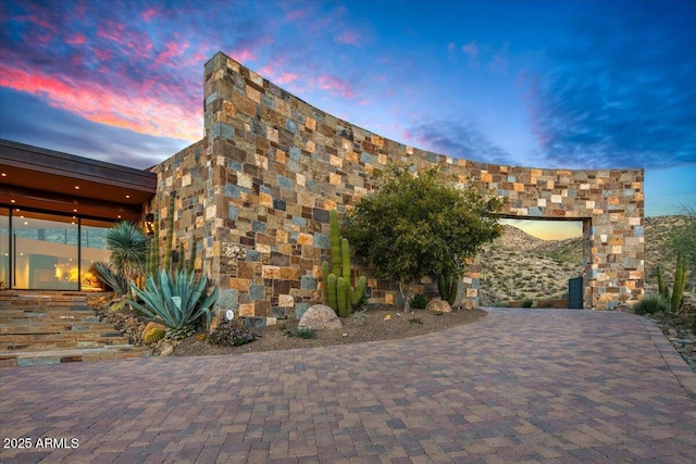 property exterior at dusk featuring stone siding