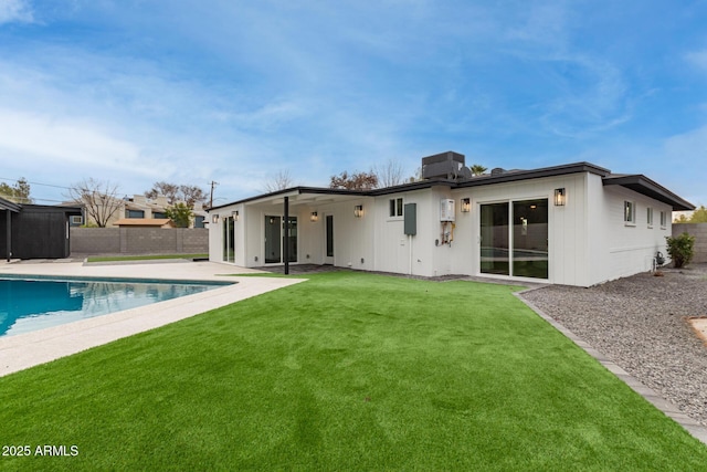 back of house with a fenced in pool, a patio, and a lawn