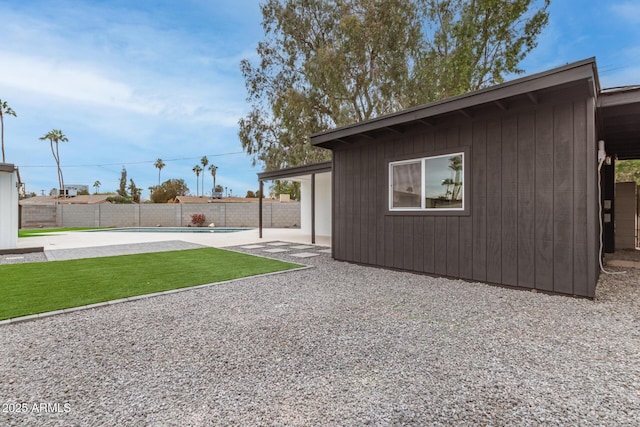 exterior space with a fenced in pool, a patio, and an outbuilding