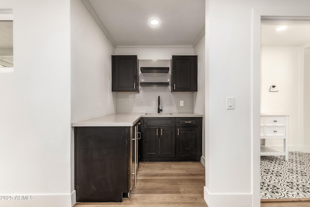 kitchen featuring tasteful backsplash, crown molding, light hardwood / wood-style floors, and sink