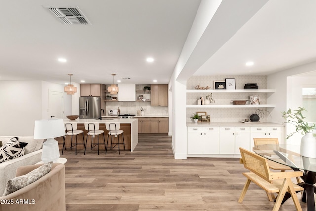 kitchen with a kitchen island, sink, stainless steel fridge, a kitchen breakfast bar, and hanging light fixtures